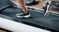 Close-up image of fit man in sneakers running fast on treadmill in gym in the morning