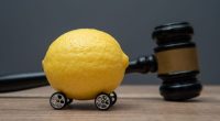 A lemon with wheels and a judge gavel. Lemon law concept.
