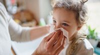 Parent wiping nose of child possibly due to flu or a cold