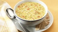 Bowl of chicken noodle soup with crackers.