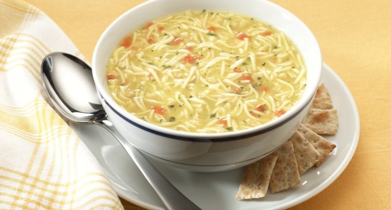 Bowl of chicken noodle soup with crackers.