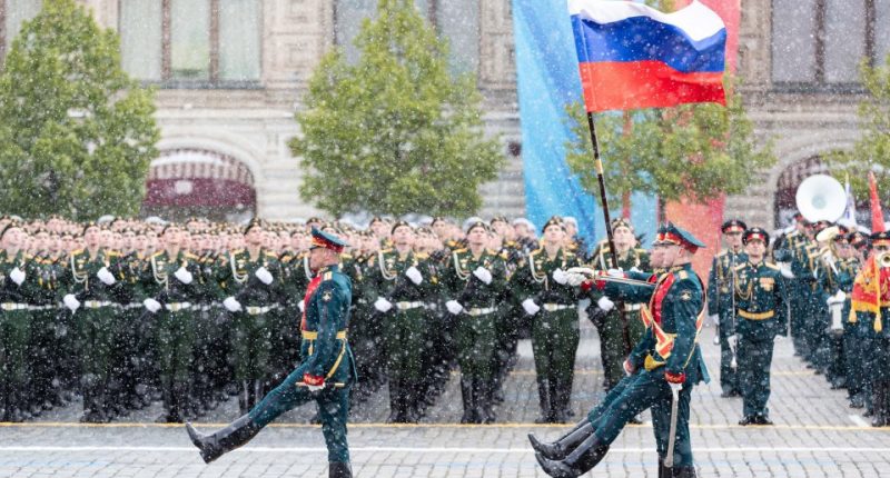 Russian honor guard soldiers marching with the national flag during a Victory Day military parade in Moscow.