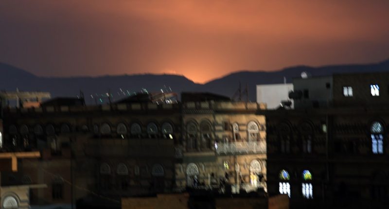 Nighttime view of Sana'a, Yemen, with an orange glow in the sky.