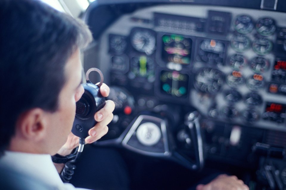 Pilot using a radio in a cockpit.
