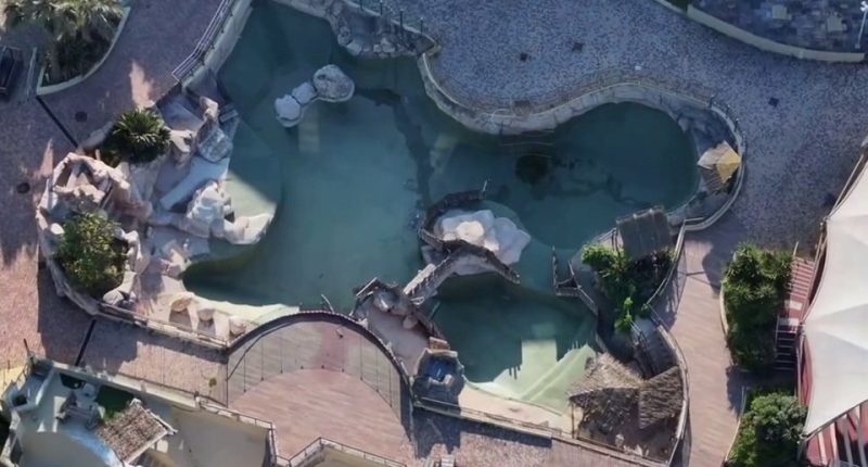 Aerial view of an abandoned marine park with two orcas and twelve dolphins.