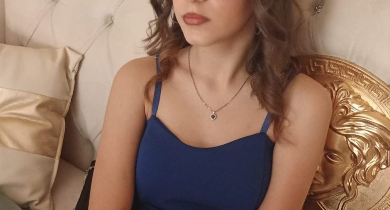 Teenage girl in blue dress and glasses.