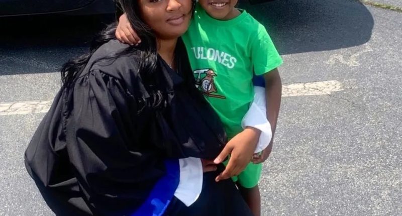 A graduating woman in a cap and gown embraces her young child.