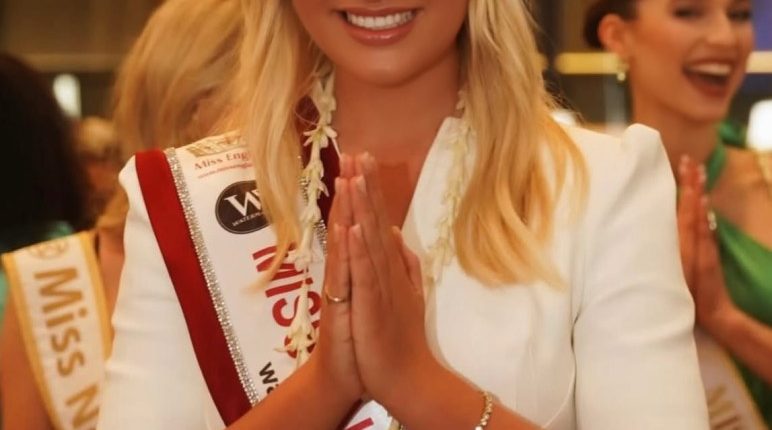 Miss England, Milla Magee, in a white dress and sash, performing a traditional greeting.