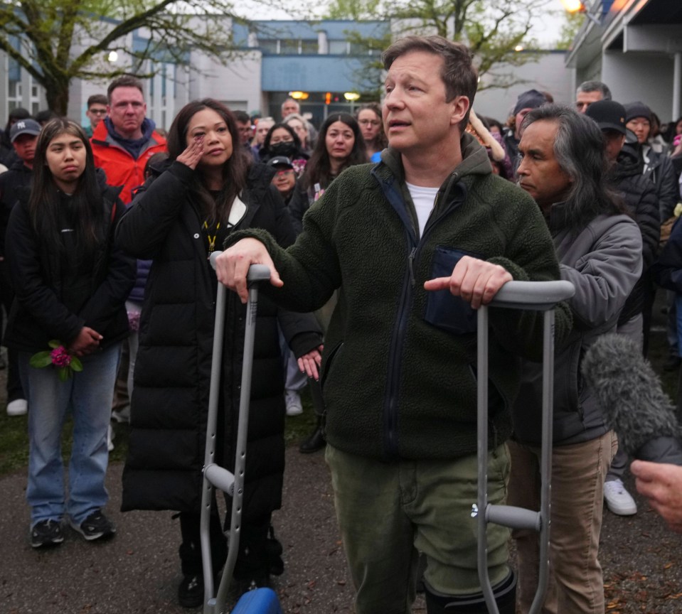 Man on crutches speaks at a vigil.