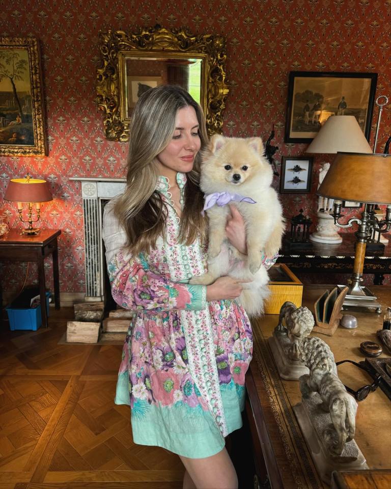 Woman in floral dress holding a Pomeranian dog.