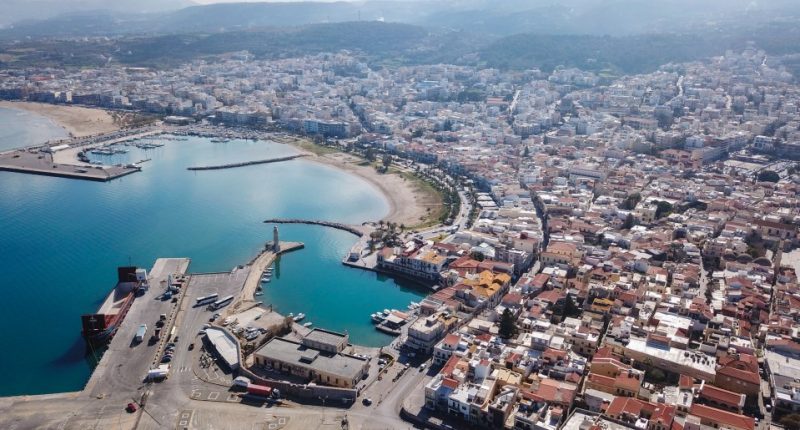 Aerial view of Heraklion, Crete, showing the city's harbor, coastline, and surrounding buildings.