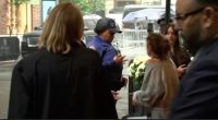 A New York City police officer speaks with a group of people near some flowers.
