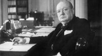 Black and white photo of Winston Churchill at his seat in the Cabinet Room at 10 Downing Street.