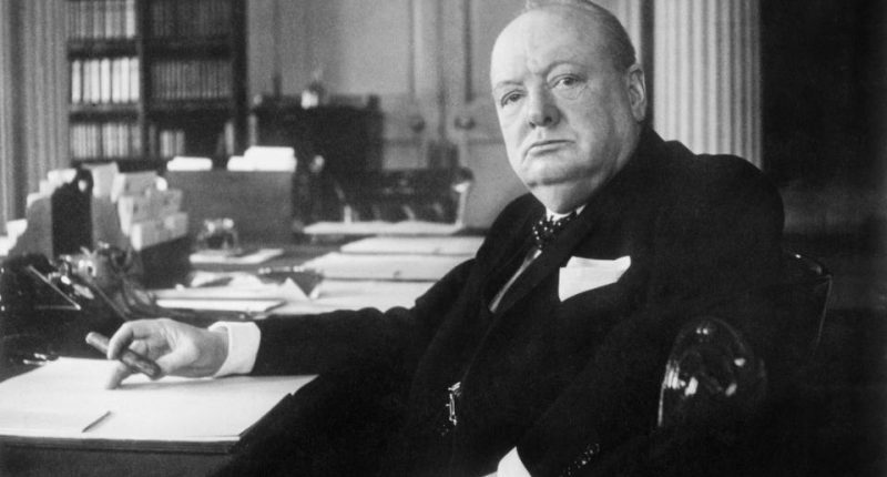 Black and white photo of Winston Churchill at his seat in the Cabinet Room at 10 Downing Street.