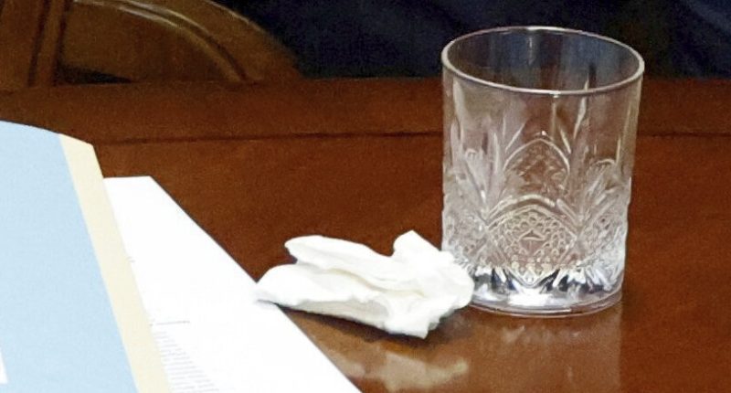 Image of a tissue, papers, and a glass on a table.
