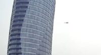 Helicopter flying near a skyscraper.