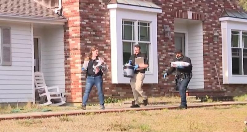 Investigators removing bags and a bucket from a house.
