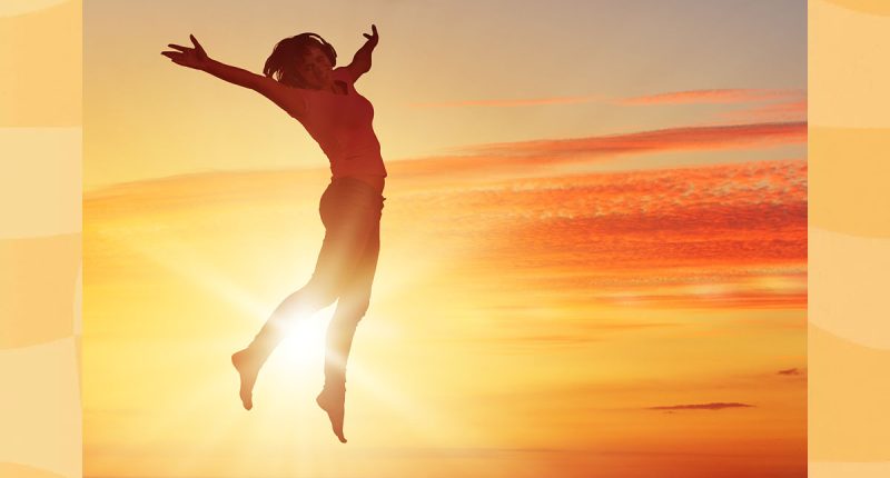Silhouette of dancer jumping against city in lights of sunrise