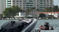 A luxury yacht partially submerged in the water near a high-rise building.