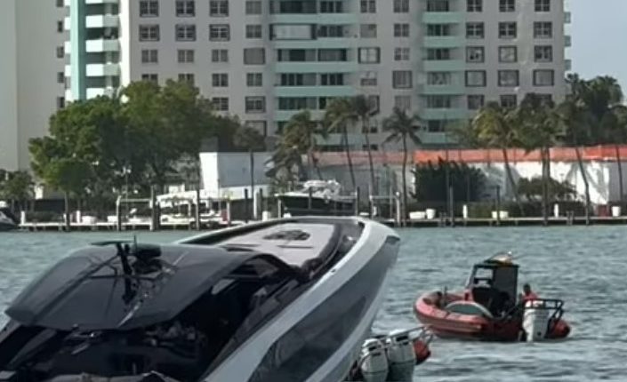 A luxury yacht partially submerged in the water near a high-rise building.