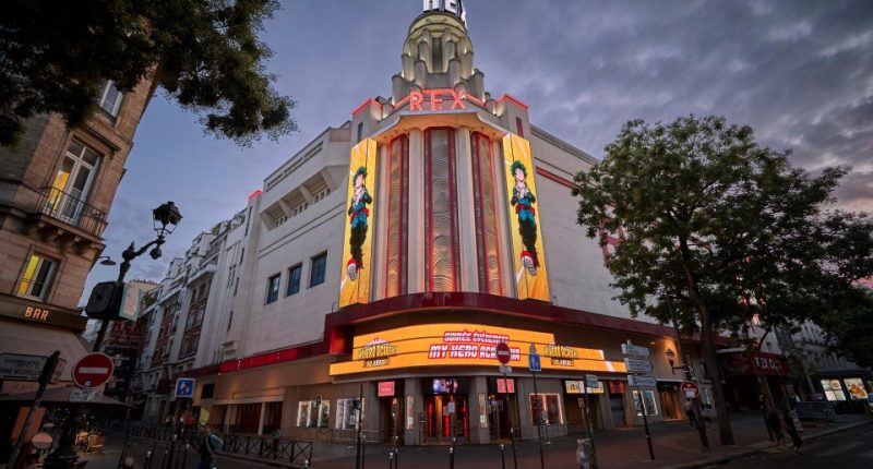 The Grand Rex cinema in Paris at dusk, showing a My Hero Academia movie poster.