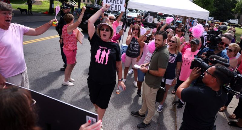 Supporters holding signs and cheering for Karen Read outside a courthouse.