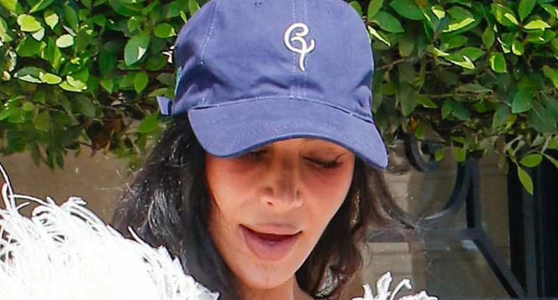 Kim Kardashian teams her feathered gown with a baseball cap