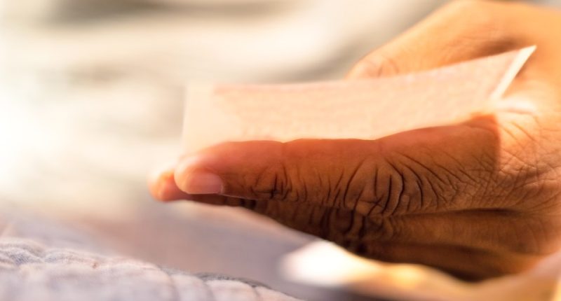A hand holding a lottery ticket.