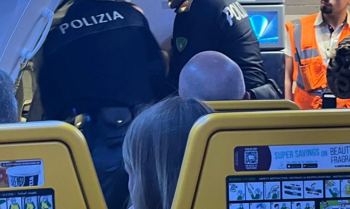 Police officers removing disruptive passengers from an airplane.