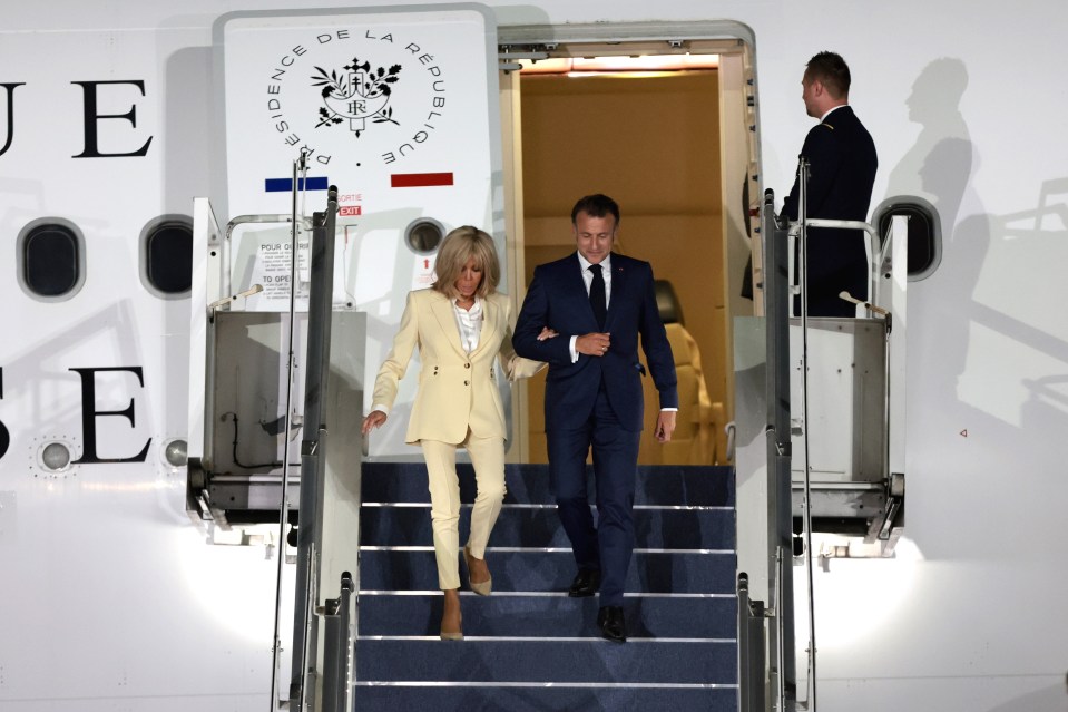 Emmanuel and Brigitte Macron disembarking from a plane.