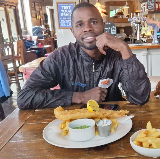 Man sitting at a pub table eating fish and chips.