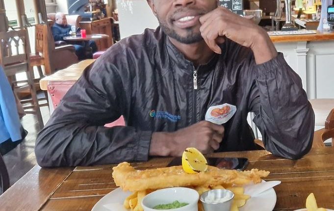 Man sitting at a pub table eating fish and chips.