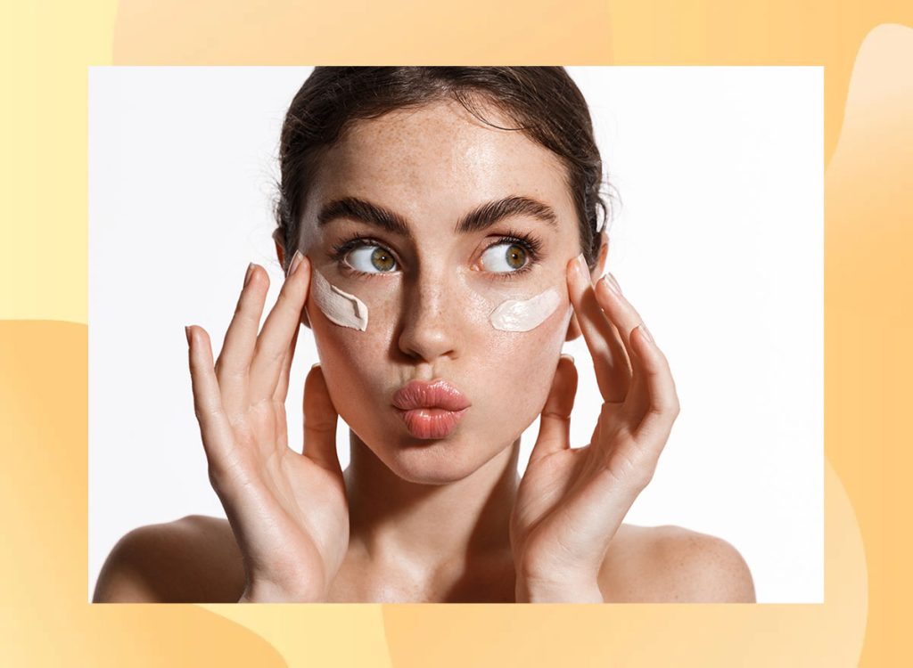 Close up beauty girl with freckles and thick eyebrows, applying moisturizing skincare cream, lotion or mask for skin lifting and anti-aging detoxifying effect, white background. 1941572701