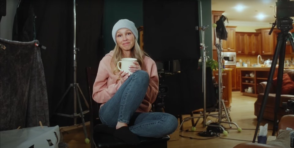 Woman holding a mug, sitting on a chair on a film set.