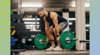 fit, muscular man doing a barbell deadlift in weight room of a gym