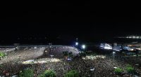 Lady Gaga performing at a large outdoor concert on Copacabana Beach at night.