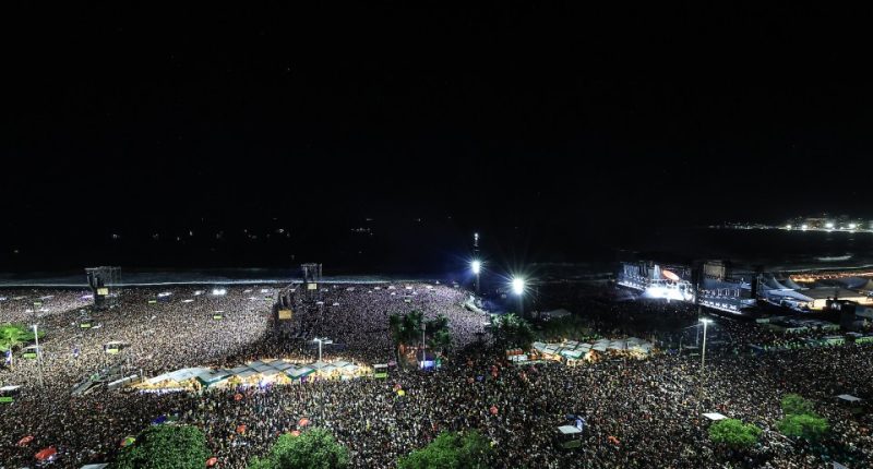 Lady Gaga performing at a large outdoor concert on Copacabana Beach at night.