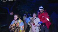 Emergency personnel evacuating residents and their dogs from a damaged building.