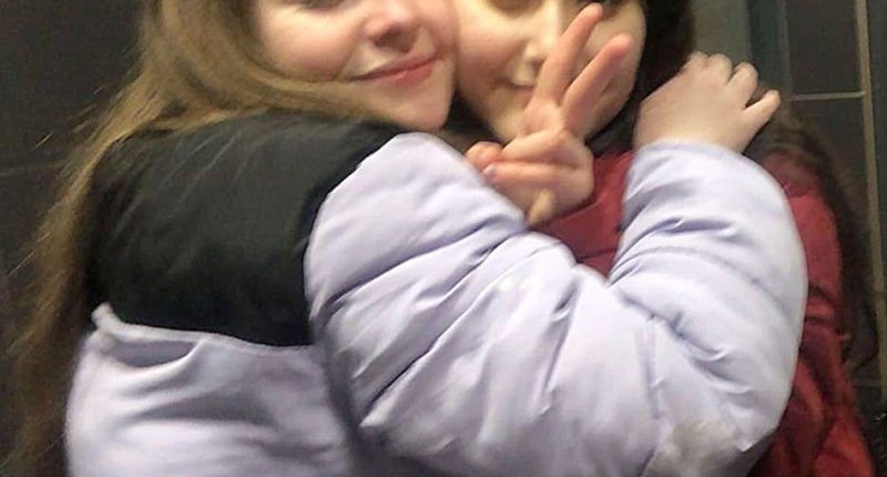 Two teenage girls hugging.