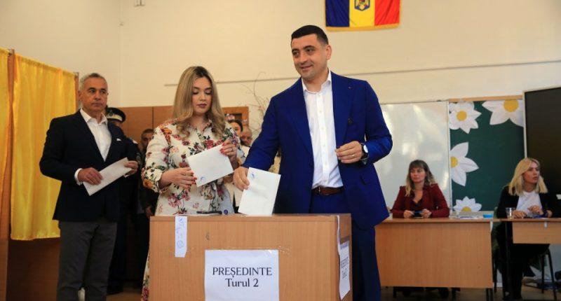 A man in a blue suit casting a ballot in a Romanian presidential election.