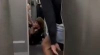 Man in shorts and barefoot assisting a passenger on an airplane.