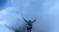Person paragliding in clouds.