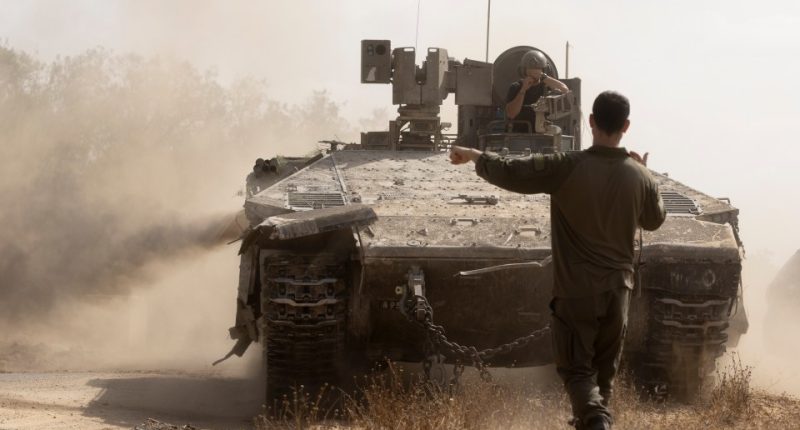 Israeli soldier directing an armored personnel carrier near the Gaza Strip border.