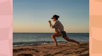 fit woman in biker shorts, a sweatshirt, and a baseball cap doing walking lunges on the beach at sunset