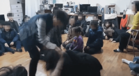 A person interacting with a group of children sitting on the floor.