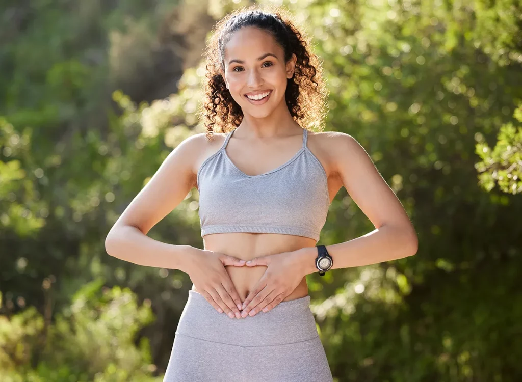 Fitness, heart hands and portrait of runner woman outdoor in park for summer training or workout. Gut health, improvement and wellness with happy sports athlete running in nature for cardio exercise