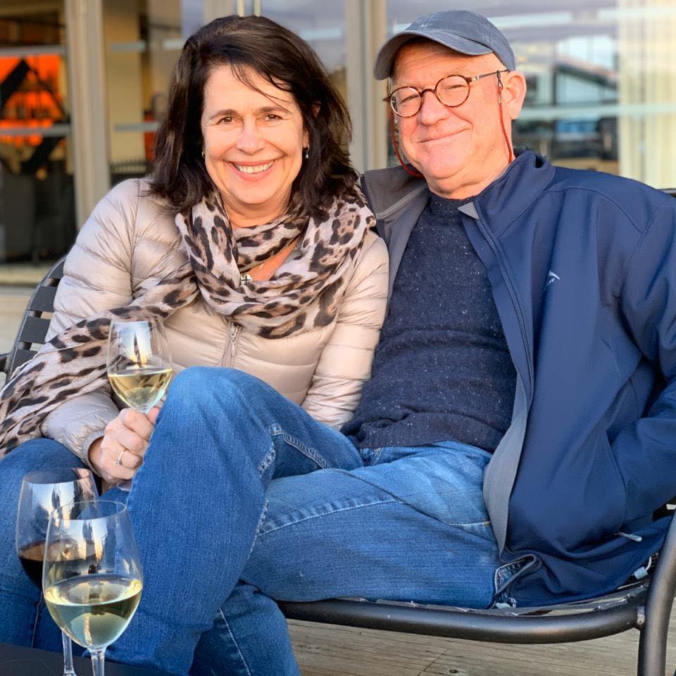 Alan and Karen Carter sitting together outdoors with wine.