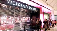 Shoppers wearing masks line up outside a Victoria's Secret store.