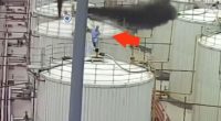 Worker on platform near industrial smoke plume.