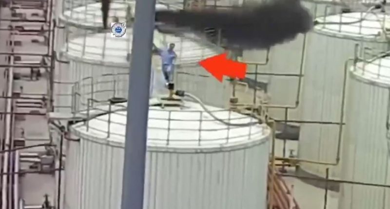 Worker on platform near industrial smoke plume.